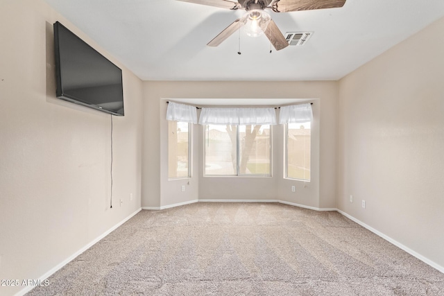 empty room featuring carpet floors, visible vents, ceiling fan, and baseboards