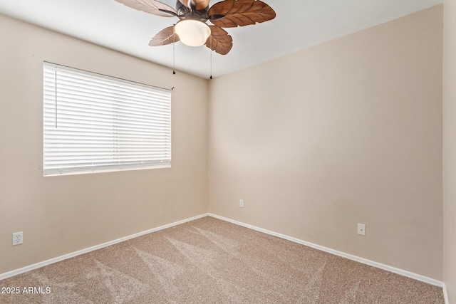 carpeted spare room featuring ceiling fan and baseboards