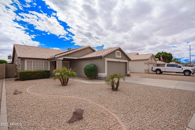 view of front of property featuring an attached garage, a tiled roof, concrete driveway, and stucco siding