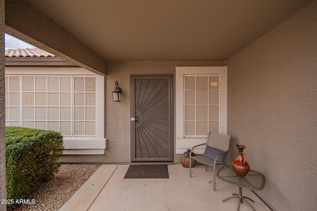 property entrance featuring a tile roof and stucco siding