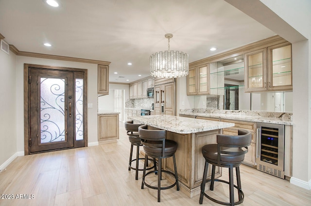 kitchen featuring light stone countertops, a center island, hanging light fixtures, light hardwood / wood-style floors, and beverage cooler