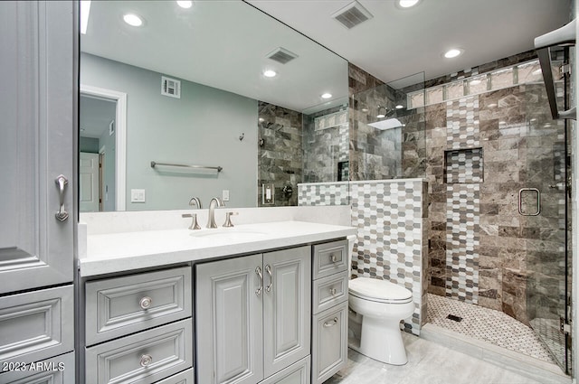 bathroom with a shower with door, vanity, toilet, and tile walls