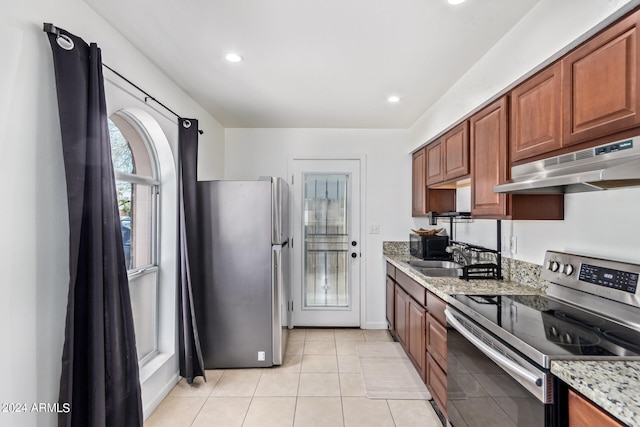 kitchen with light stone counters, light tile patterned floors, appliances with stainless steel finishes, and sink