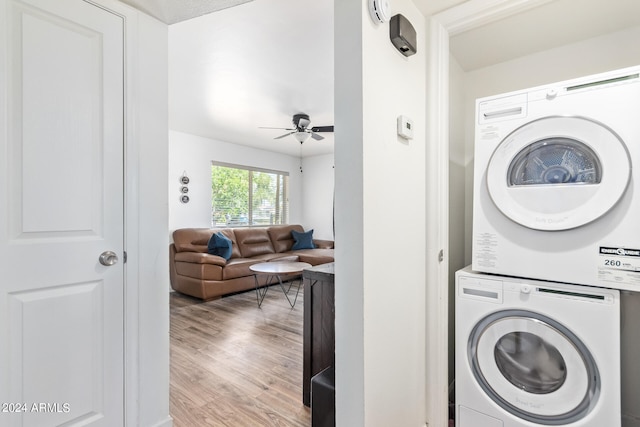 clothes washing area featuring stacked washer / drying machine, ceiling fan, and light hardwood / wood-style flooring