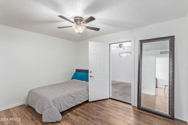 bedroom with ceiling fan, a textured ceiling, and dark hardwood / wood-style floors