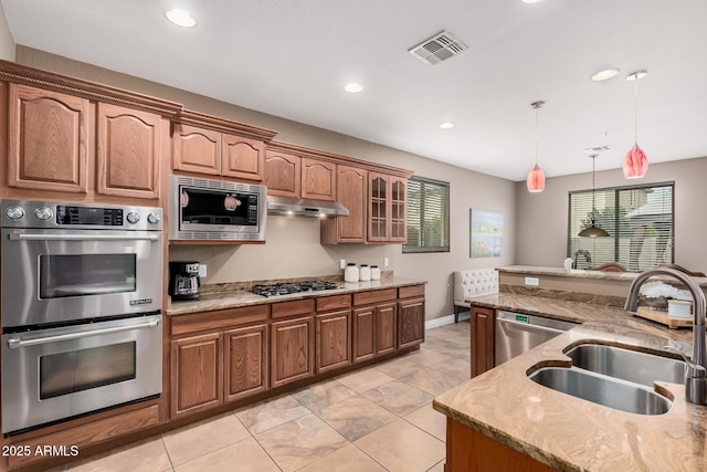 kitchen featuring visible vents, under cabinet range hood, hanging light fixtures, stainless steel appliances, and a sink