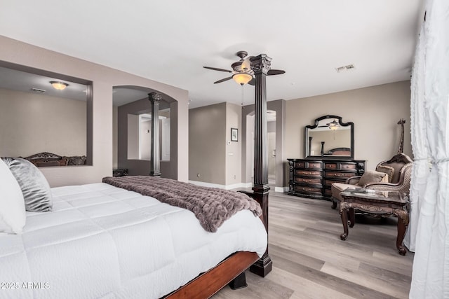 bedroom featuring a ceiling fan, visible vents, ornate columns, light wood finished floors, and arched walkways