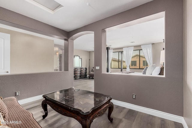 interior space featuring baseboards, arched walkways, and wood finished floors