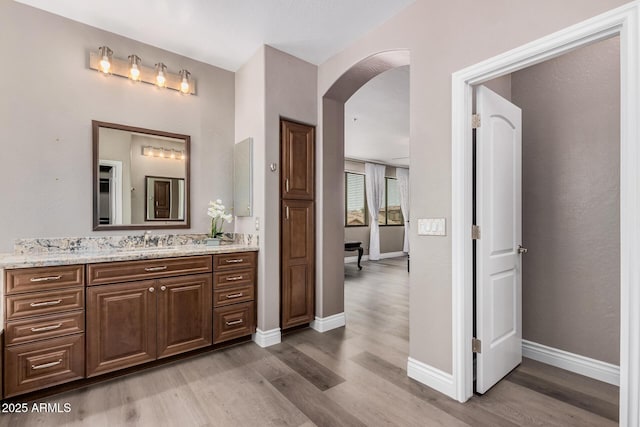 bathroom with baseboards, wood finished floors, and vanity