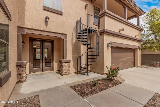 doorway to property with french doors, concrete driveway, an attached garage, and stucco siding