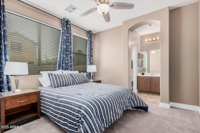 bedroom featuring ensuite bath, carpet flooring, arched walkways, and visible vents