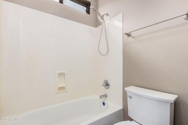 bathroom featuring toilet, shower / bathtub combination, and a textured wall