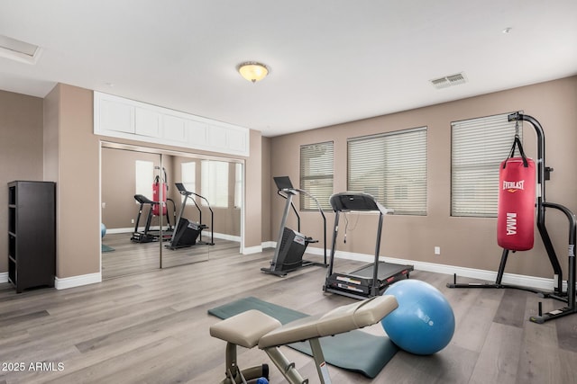 exercise area with visible vents, baseboards, and light wood finished floors