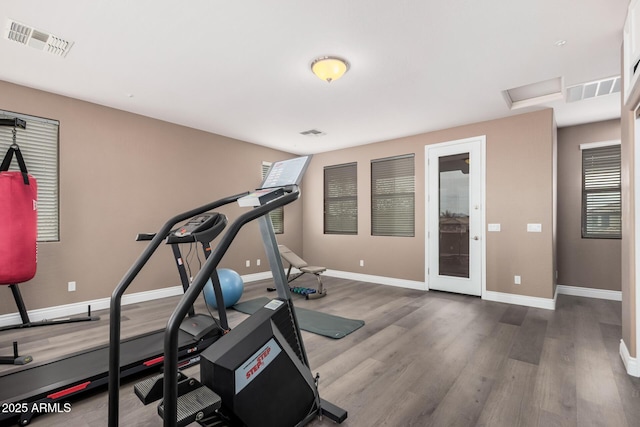 workout area with visible vents, baseboards, and wood finished floors