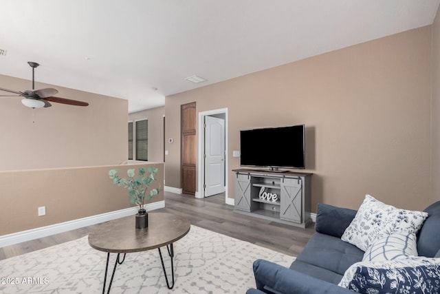 living room featuring visible vents, baseboards, wood finished floors, and a ceiling fan