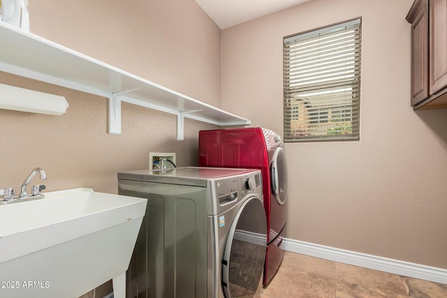 clothes washing area with baseboards, cabinet space, independent washer and dryer, and a sink