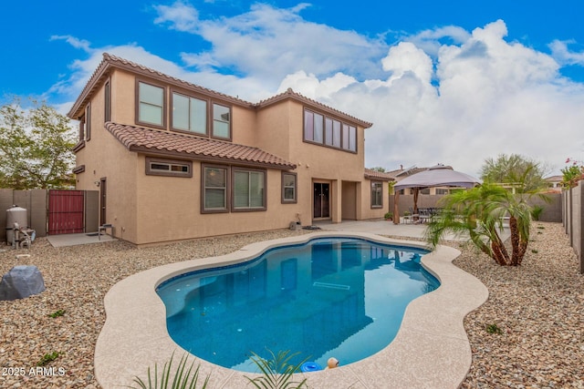 rear view of house featuring stucco siding, a tile roof, a gate, a patio, and a fenced backyard