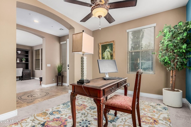 office area with arched walkways, visible vents, ceiling fan, and baseboards