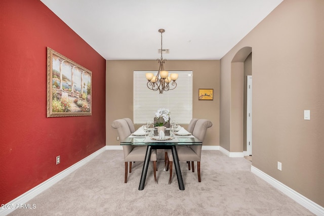 dining room with baseboards, light carpet, arched walkways, and a chandelier