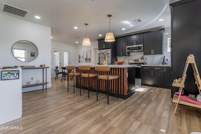 kitchen featuring light wood finished floors, visible vents, dark cabinets, stainless steel appliances, and french doors