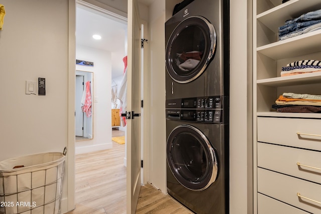 laundry room with stacked washer and dryer, baseboards, laundry area, and light wood-style floors