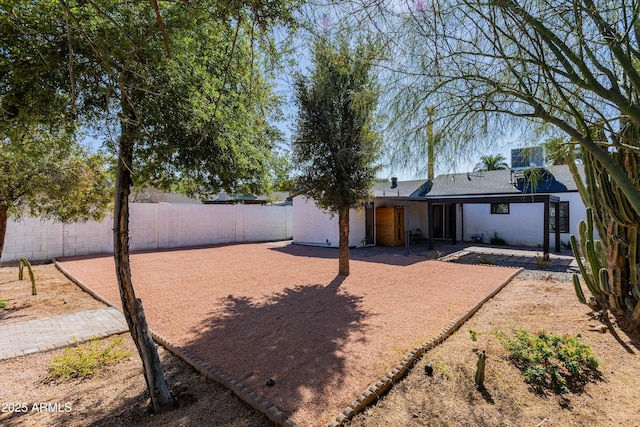 rear view of property with a fenced backyard and a patio