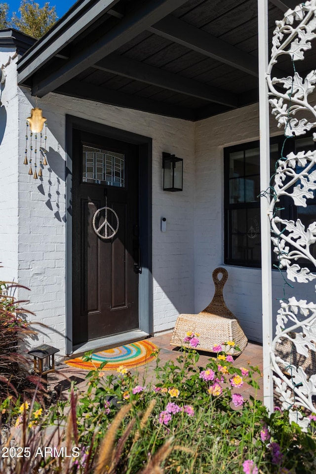 entrance to property featuring a porch and brick siding