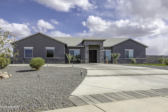 view of front of home featuring stucco siding, stone siding, and curved driveway