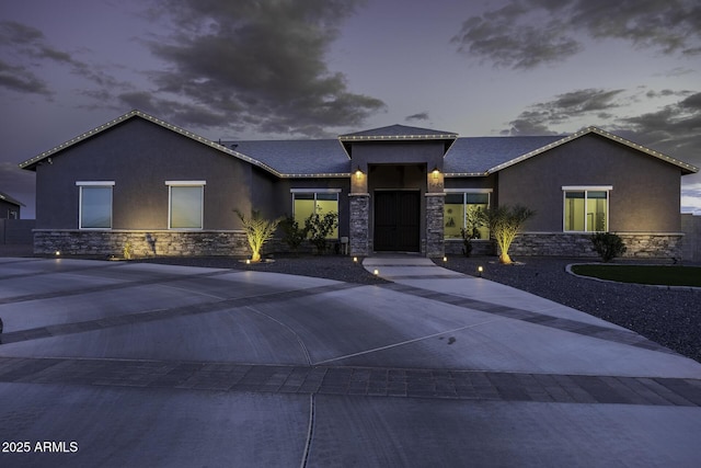view of front of property featuring stone siding, stucco siding, and concrete driveway