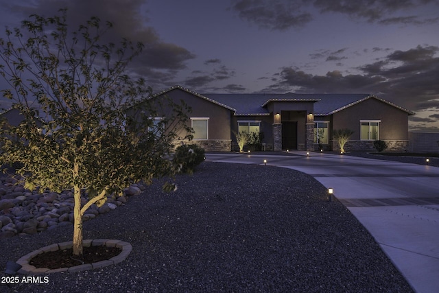view of front of home with stone siding, driveway, and stucco siding