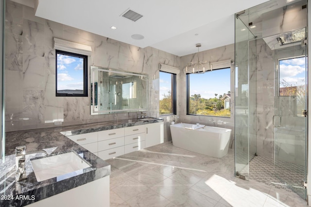 bathroom with independent shower and bath, tile walls, vanity with extensive cabinet space, double sink, and tile floors