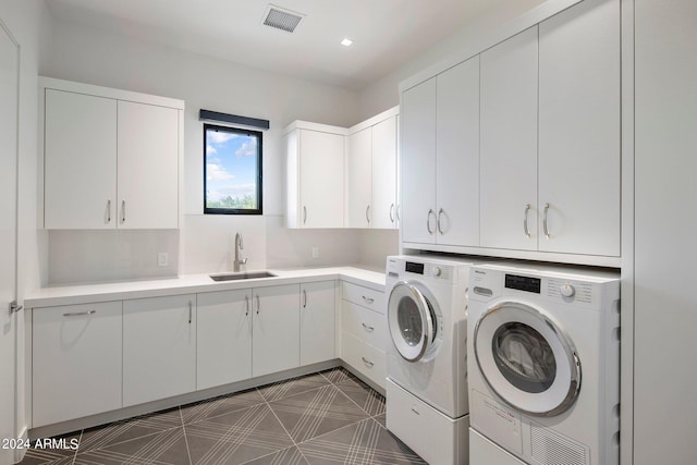 laundry area with cabinets, sink, separate washer and dryer, and dark tile floors