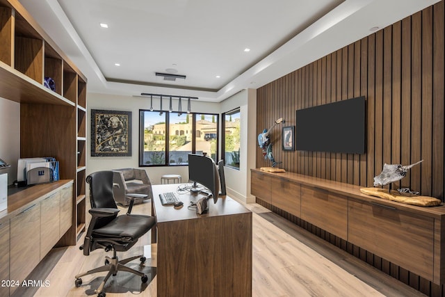 office space featuring a tray ceiling and light wood-type flooring