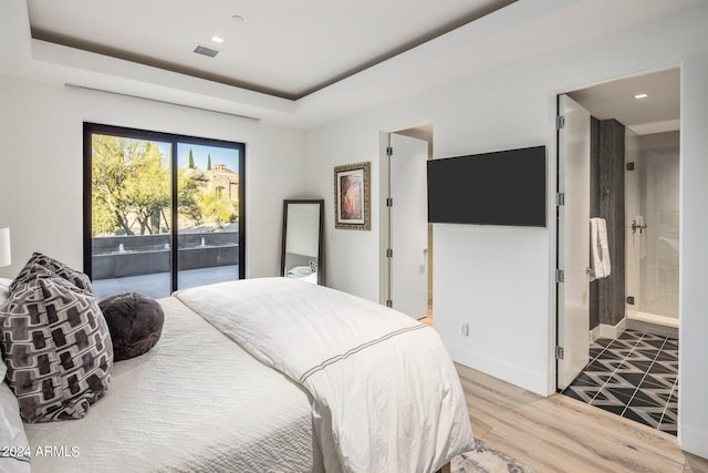 bedroom featuring ensuite bath, wood-type flooring, and access to exterior