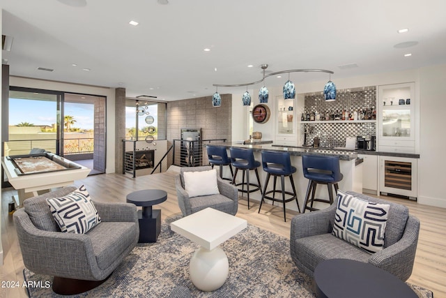 living room with bar, wine cooler, and light wood-type flooring