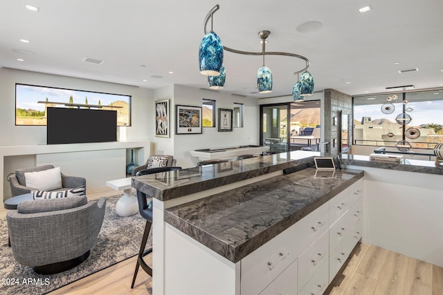 kitchen featuring light hardwood / wood-style flooring, dark stone counters, and white cabinets