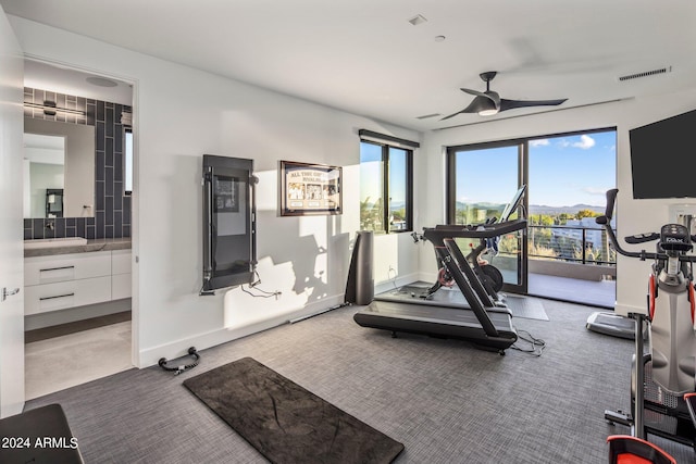 workout room featuring ceiling fan and carpet