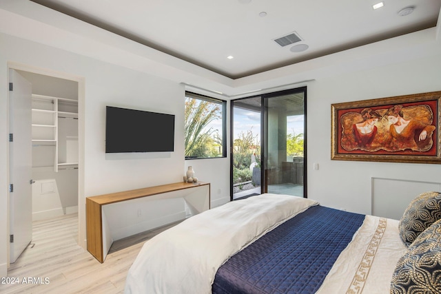 bedroom featuring a closet, a spacious closet, access to outside, and light wood-type flooring