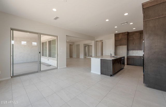 kitchen with open floor plan, tasteful backsplash, visible vents, and light stone countertops