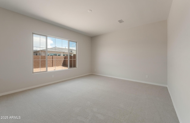 spare room with carpet floors, visible vents, and baseboards