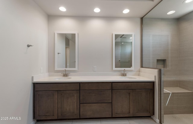 full bath featuring a tile shower, double vanity, a sink, and recessed lighting