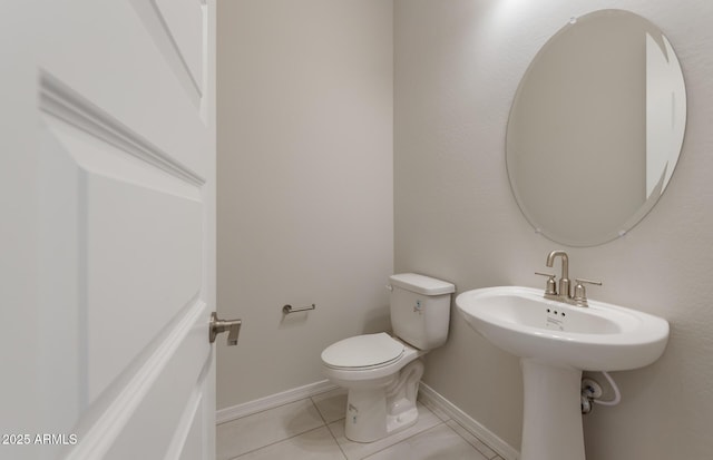 half bathroom featuring tile patterned floors, toilet, and baseboards