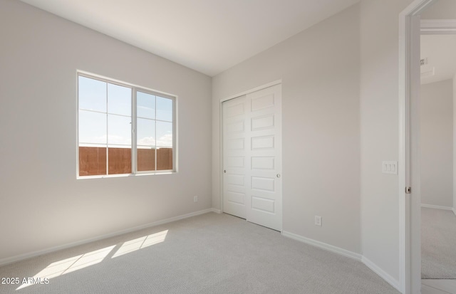 unfurnished bedroom with light carpet, a closet, and baseboards