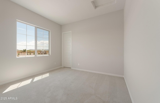 unfurnished room featuring attic access, baseboards, and light colored carpet