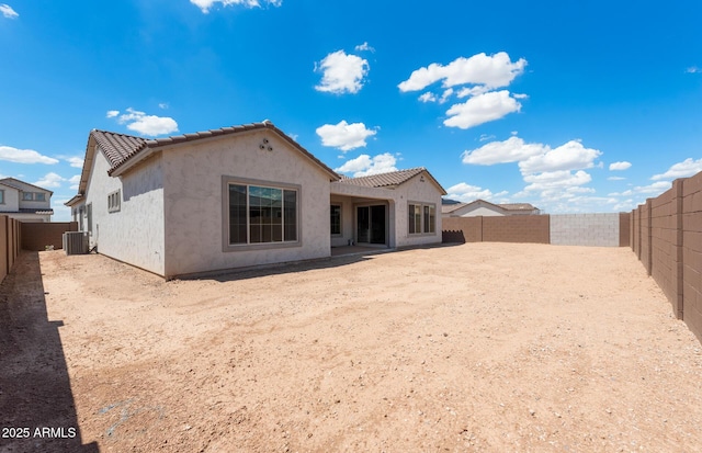 rear view of property featuring a tile roof, a fenced backyard, central AC, and stucco siding