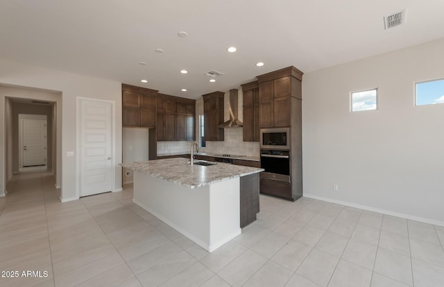 kitchen with stainless steel appliances, a sink, visible vents, wall chimney range hood, and backsplash