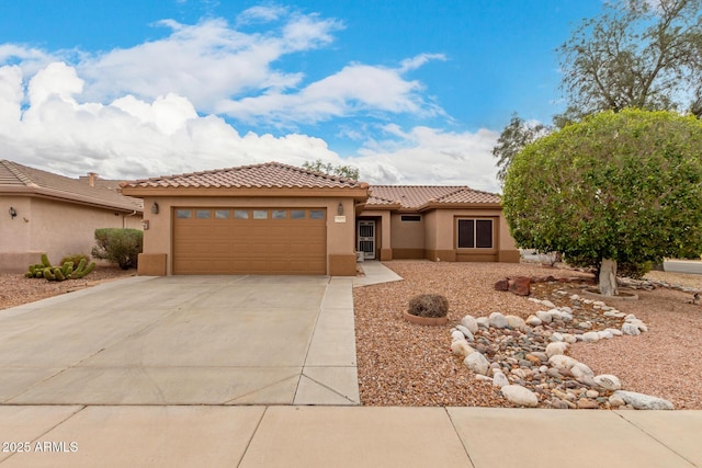 view of front facade with a tile roof, concrete driveway, an attached garage, and stucco siding