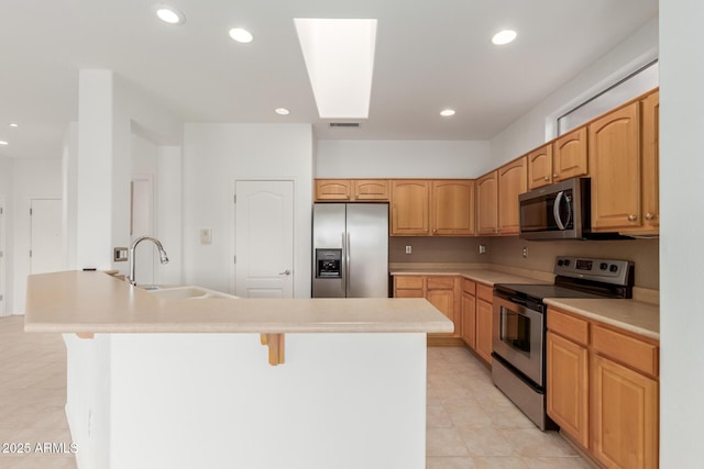 kitchen with a kitchen bar, a kitchen island with sink, a sink, recessed lighting, and appliances with stainless steel finishes