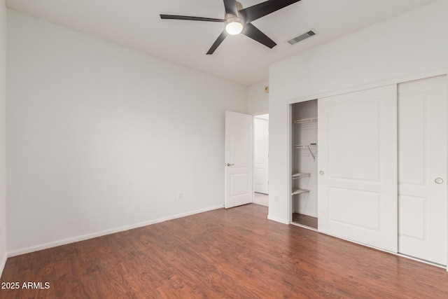 unfurnished bedroom featuring a closet, visible vents, baseboards, and wood finished floors