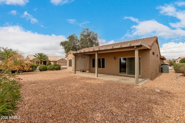 rear view of house with central AC unit, a tiled roof, a patio area, and stucco siding